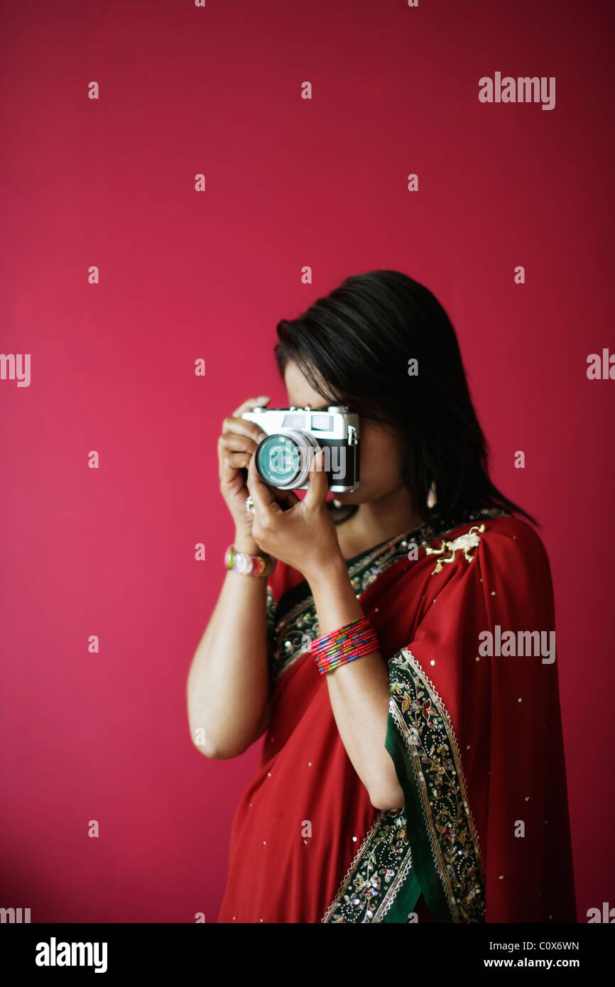 Punjabi woman in red sari takes picture with old film camera Stock Photo