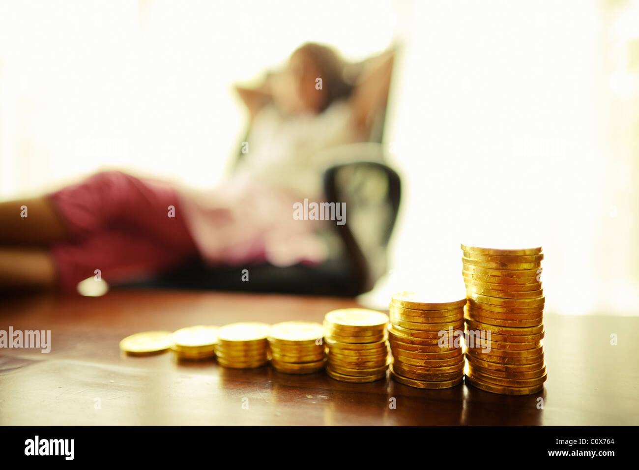 Investing in gold. Girl with stacked chocolate gold coins. Stock Photo