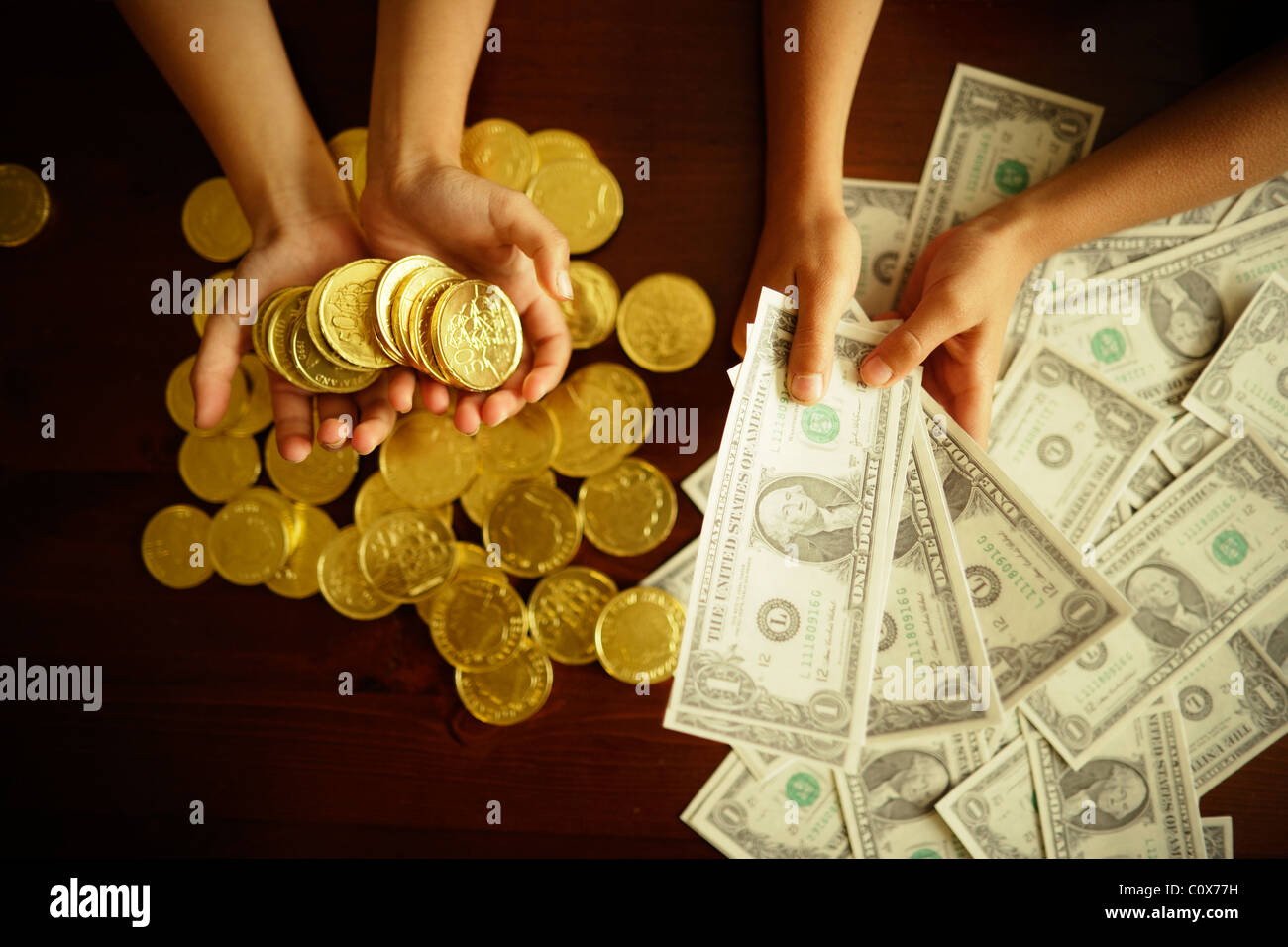Investment options. Gold versus US dollar. Children hold fake printed dollars and chocolate coins. Stock Photo