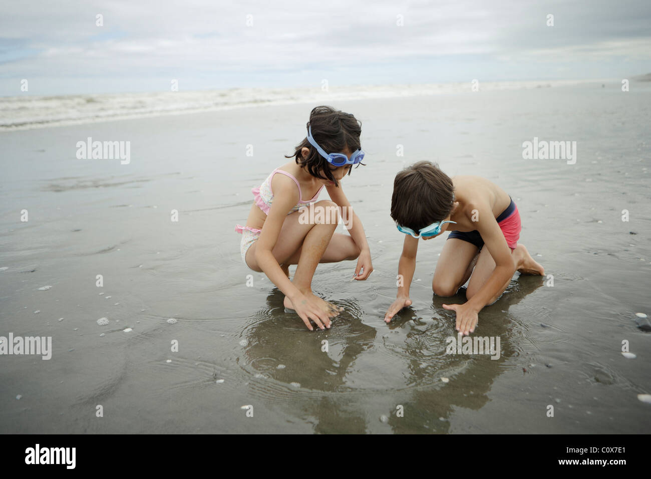 Brother and sister, mixed race, play in the sea. Manawatu, New Zealand. Stock Photo