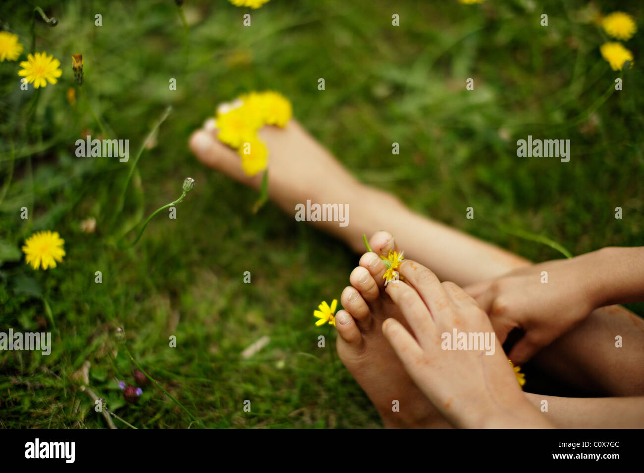 Girl puts yellow flowers between her toes. Stock Photo