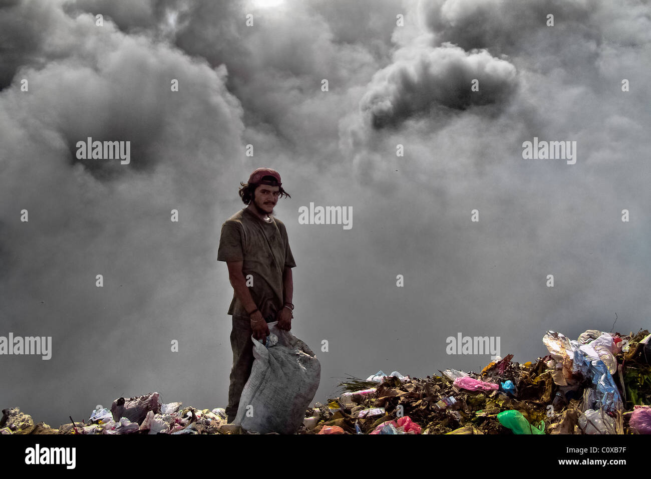 A Nicaraguan boy works on the burning pile of garbage in the garbage dump La Chureca, Managua, Nicaragua. Stock Photo