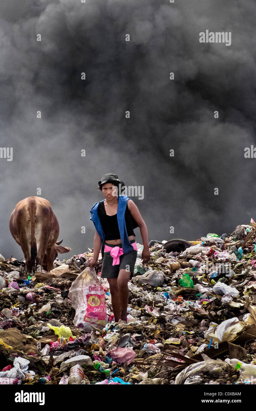 A Nicaraguan girl works on the burning pile of garbage in the garbage dump La Chureca, Managua, Nicaragua. Stock Photo