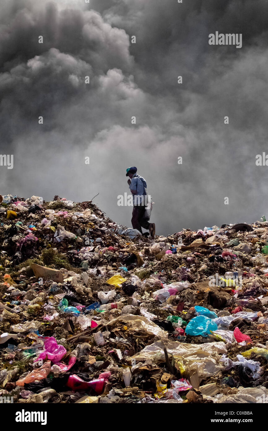 A Nicaraguan man works on the burning pile of garbage in the garbage dump La Chureca, Managua, Nicaragua. Stock Photo