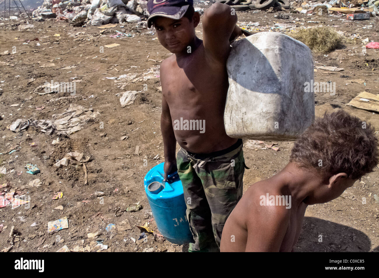 A Nicaraguan boy carries barrels of contaminated water for drinking in the garbage dump La Chureca, Managua, Nicaragua. Stock Photo