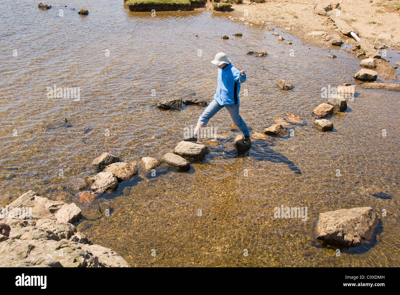 Woman using a river crossing, Lake District, England, UK Stock Photo