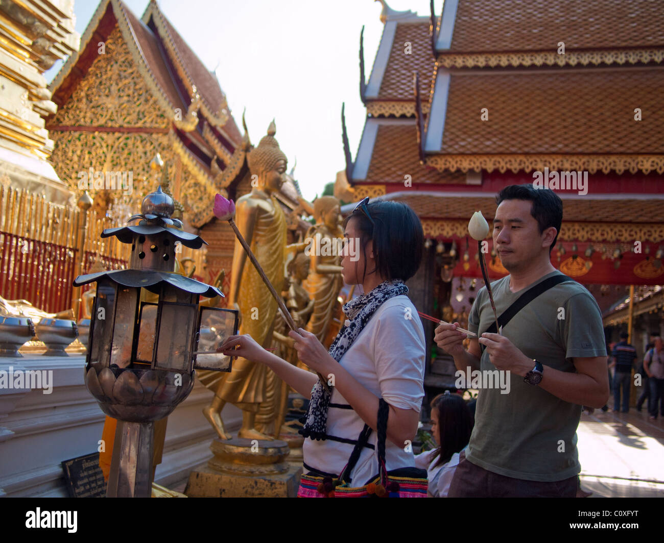 Young couple lighting the candle and incense to pay respect to the Buddha Stock Photo