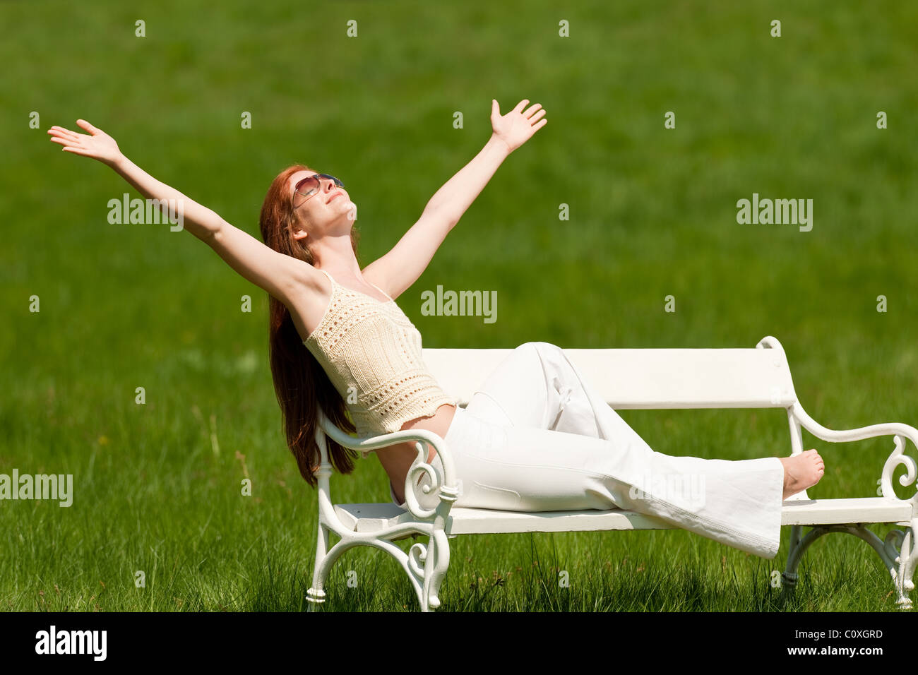Red hair woman sitting on white bench in park Stock Photo - Alamy
