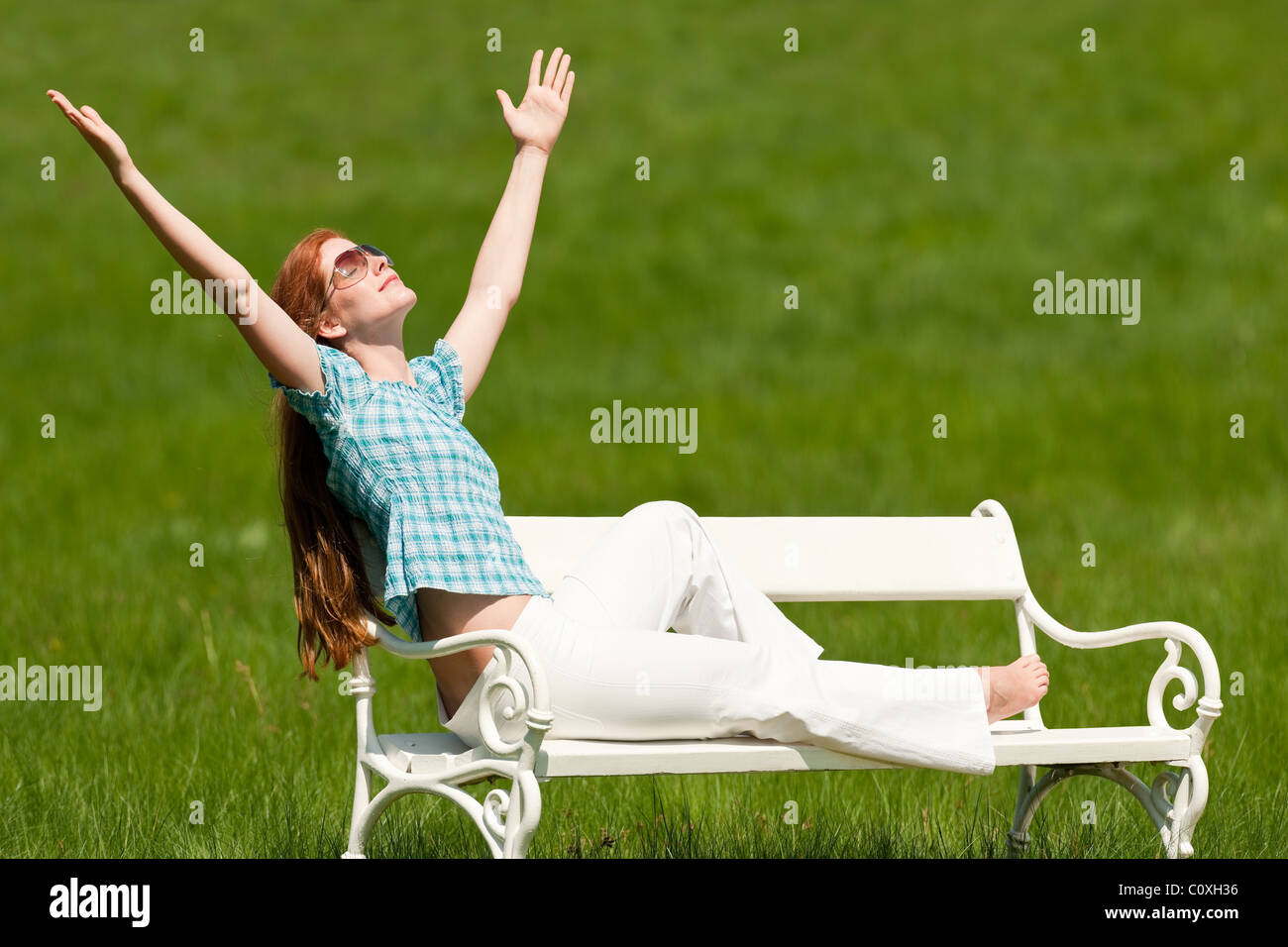 Red hair woman sitting on white bench in park Stock Photo - Alamy