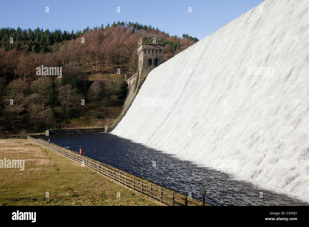 Water flowing, stone tower, trees on hillside Howden Dam at Upper Derwent Valley Reservoir in the Peak District, Derbyshire Stock Photo