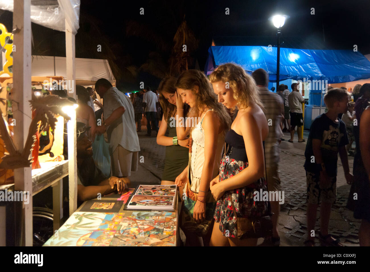 Tourist girls looking at jewellery and art in the night market at Oistins, Barbados Stock Photo