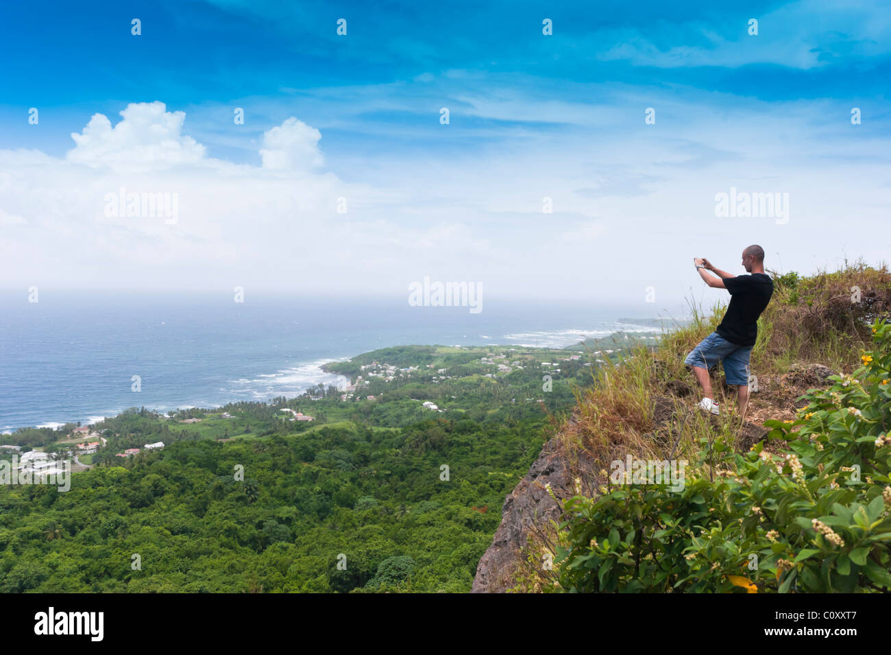 Young tourist photographs the Atlantic ocean from the east coast of Barbados, a clifftop viewpoint Stock Photo