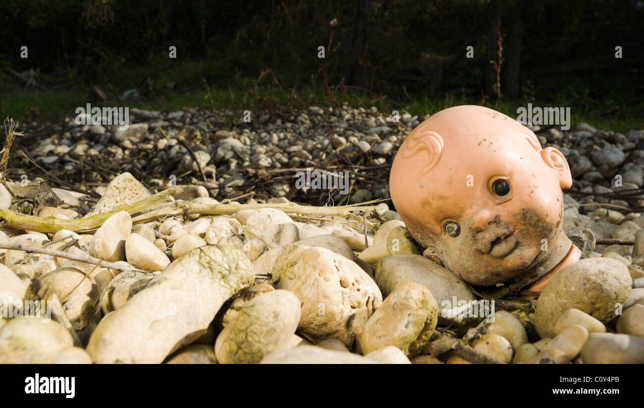 Muddy doll head found by a river Stock Photo