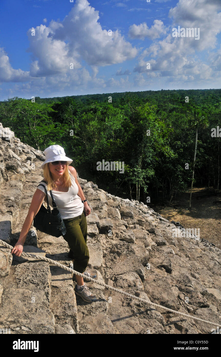 Woman climbing the Nohoch Mul pyramid at the Mayan ruins of Coba