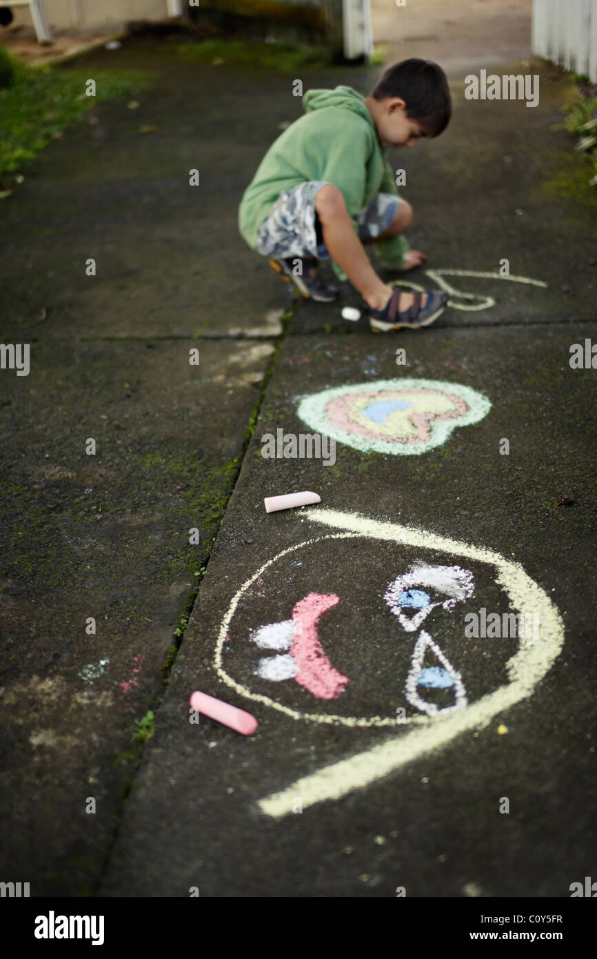 Boy drawing on path with chalk Stock Photo