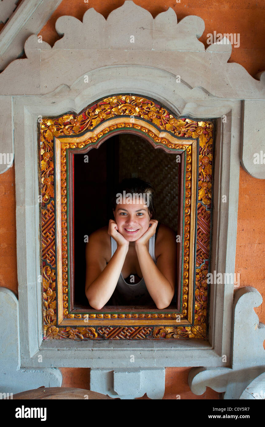 Attractive Australian teenager on holiday framed in a traditional shuttered Balinese window Stock Photo