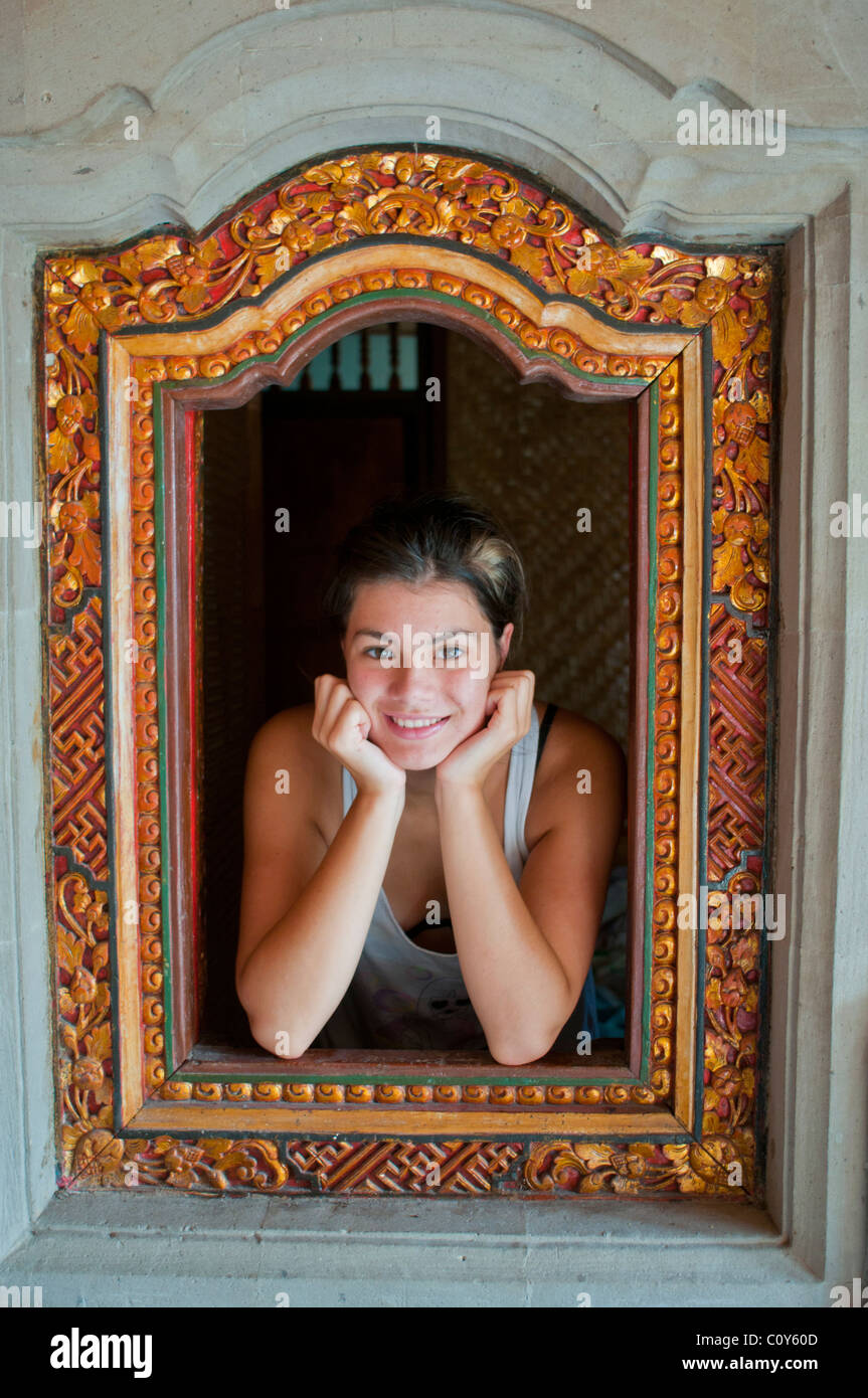 Attractive Australian teenager on holiday framed in a traditional shuttered Balinese window Stock Photo