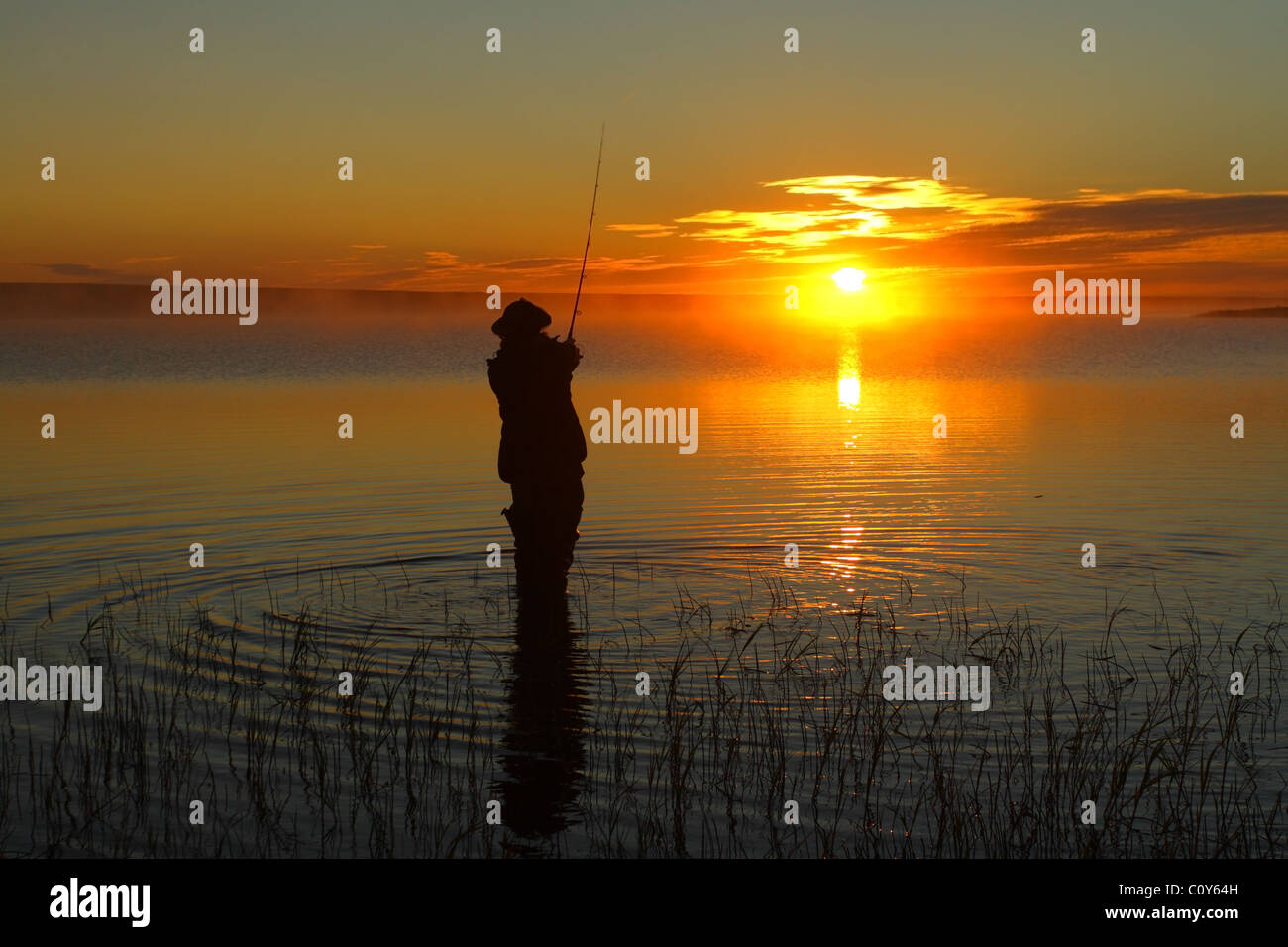 Man fishing at the lake at sunset in the north of Russia. Stock Photo