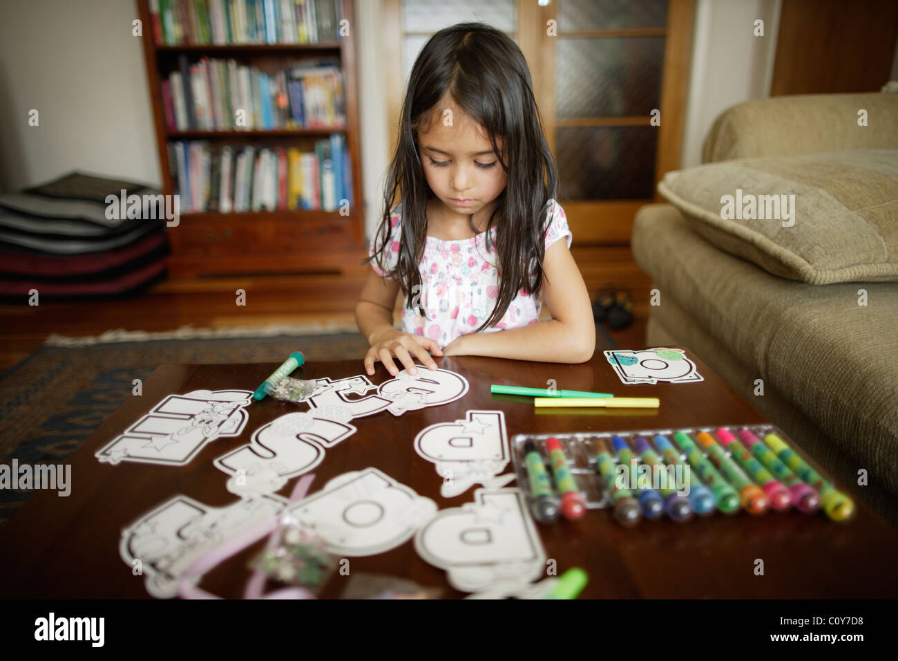 Six year old girl works on craft set of large letters to colour in and decorate Stock Photo