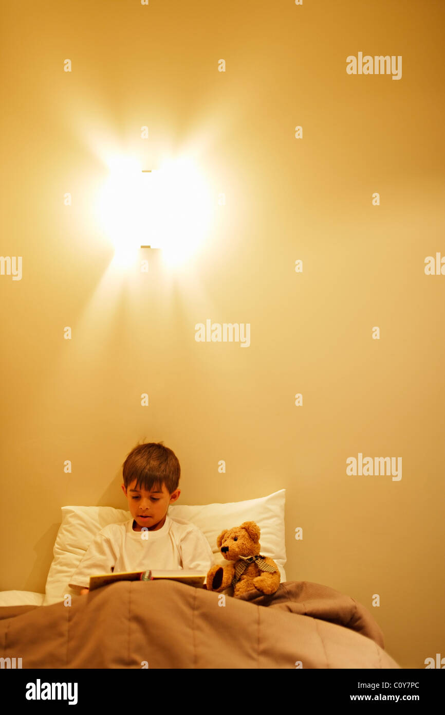 Eight year old boy reads Ted a bedtime story Stock Photo