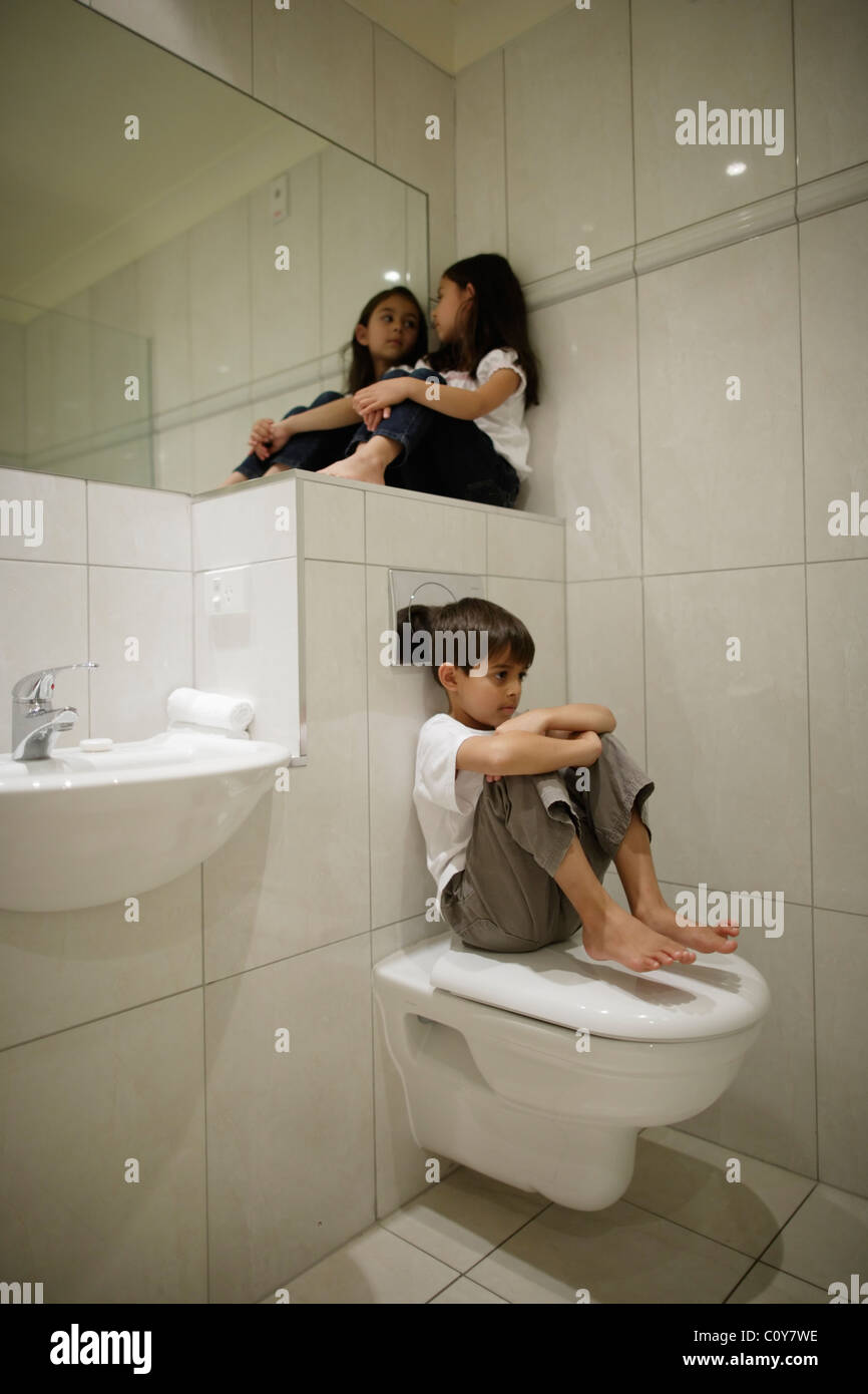 Boy and girl sitting in bathroom Stock Photo