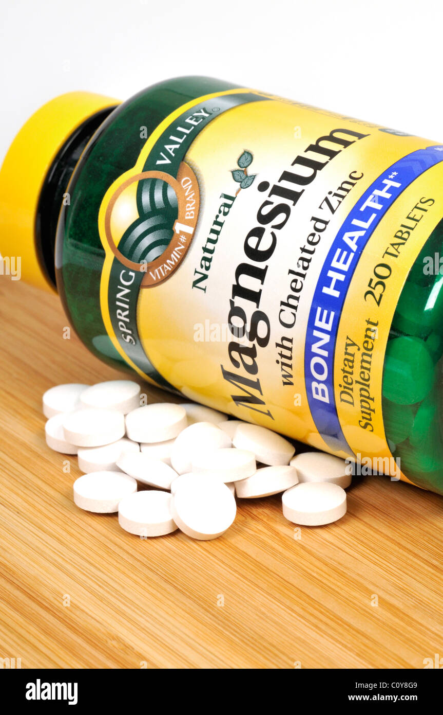 Bottle of Spring Valley Magnesium dietary supplement with tablets scattered. Stock Photo