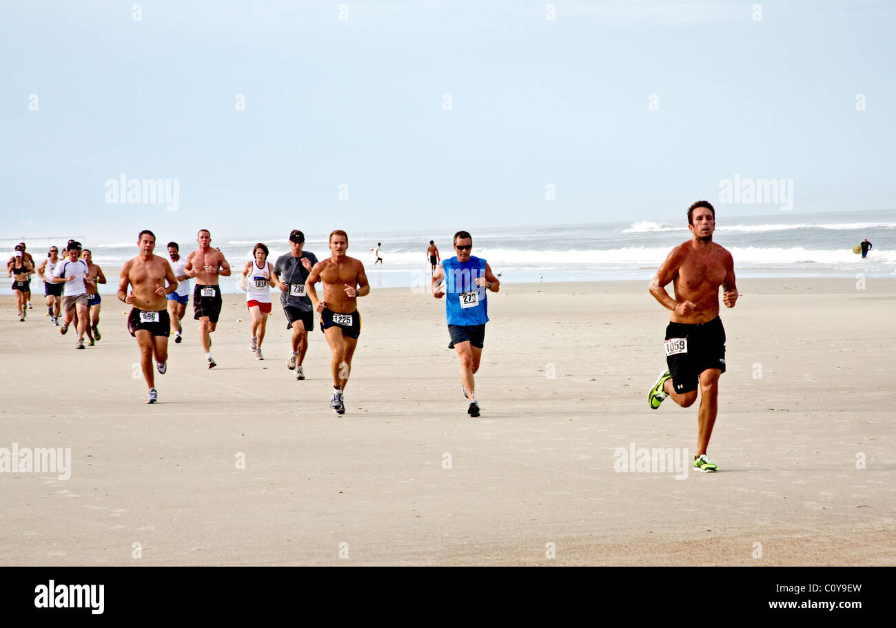 Runners running down the beach in a race by the ocean on the sand in Jacksonville Beach, Florida Stock Photo