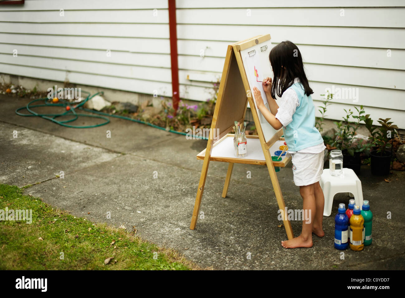 Girl painting on easel in back yard. Stock Photo