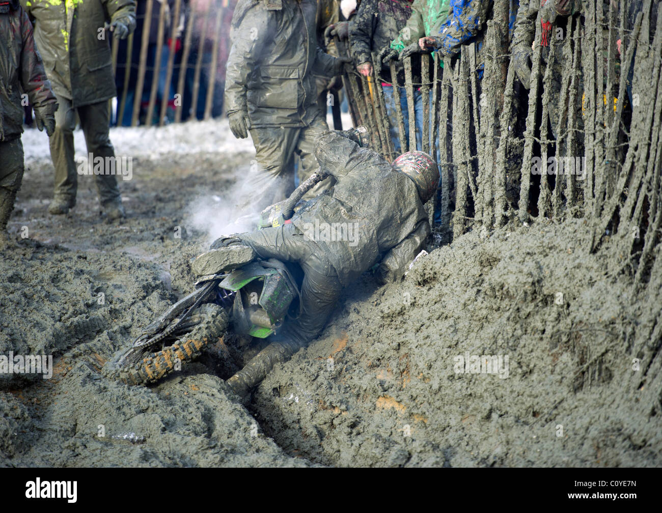 Man fallen off stuck in muddy motocross scrambling motorcycle bike in mud hole bog with steam rising Stock Photo