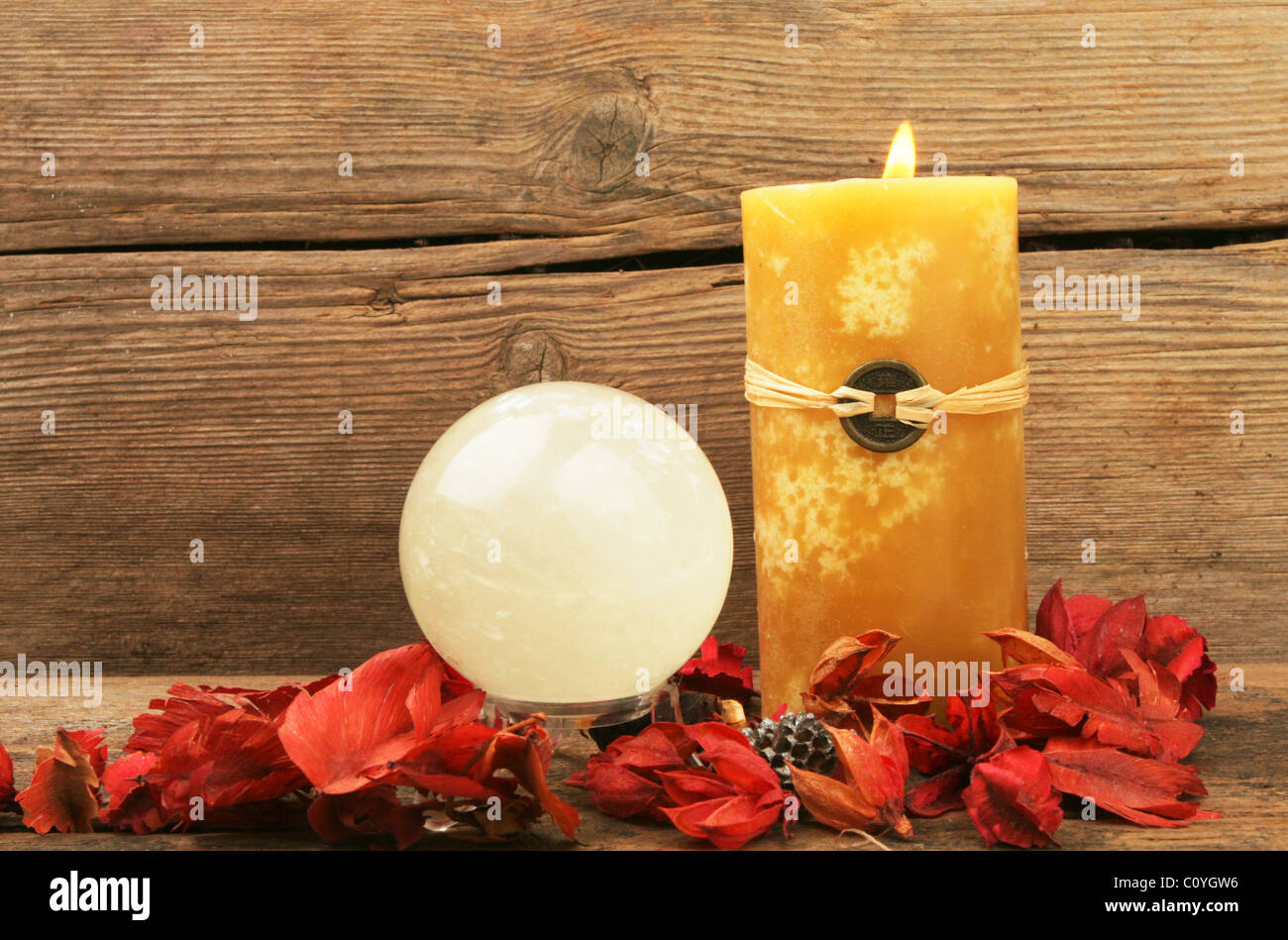 Burning feng shui candle, dried flowers and a crystal ball Stock Photo