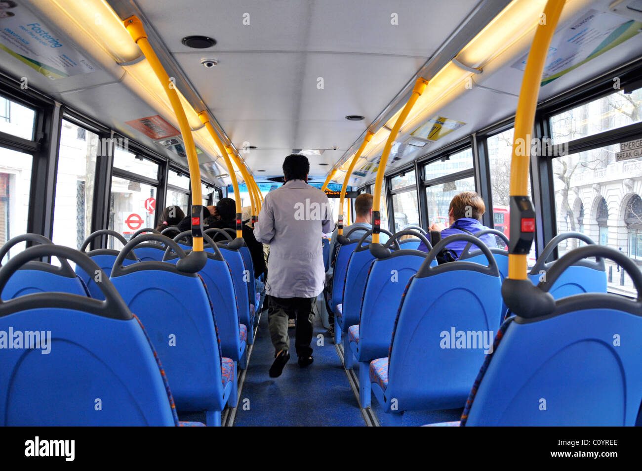 Inside London double decker bus top deck interior back view of passengers top deck one standing to exit others seated view of bus stop sign England UK Stock Photo