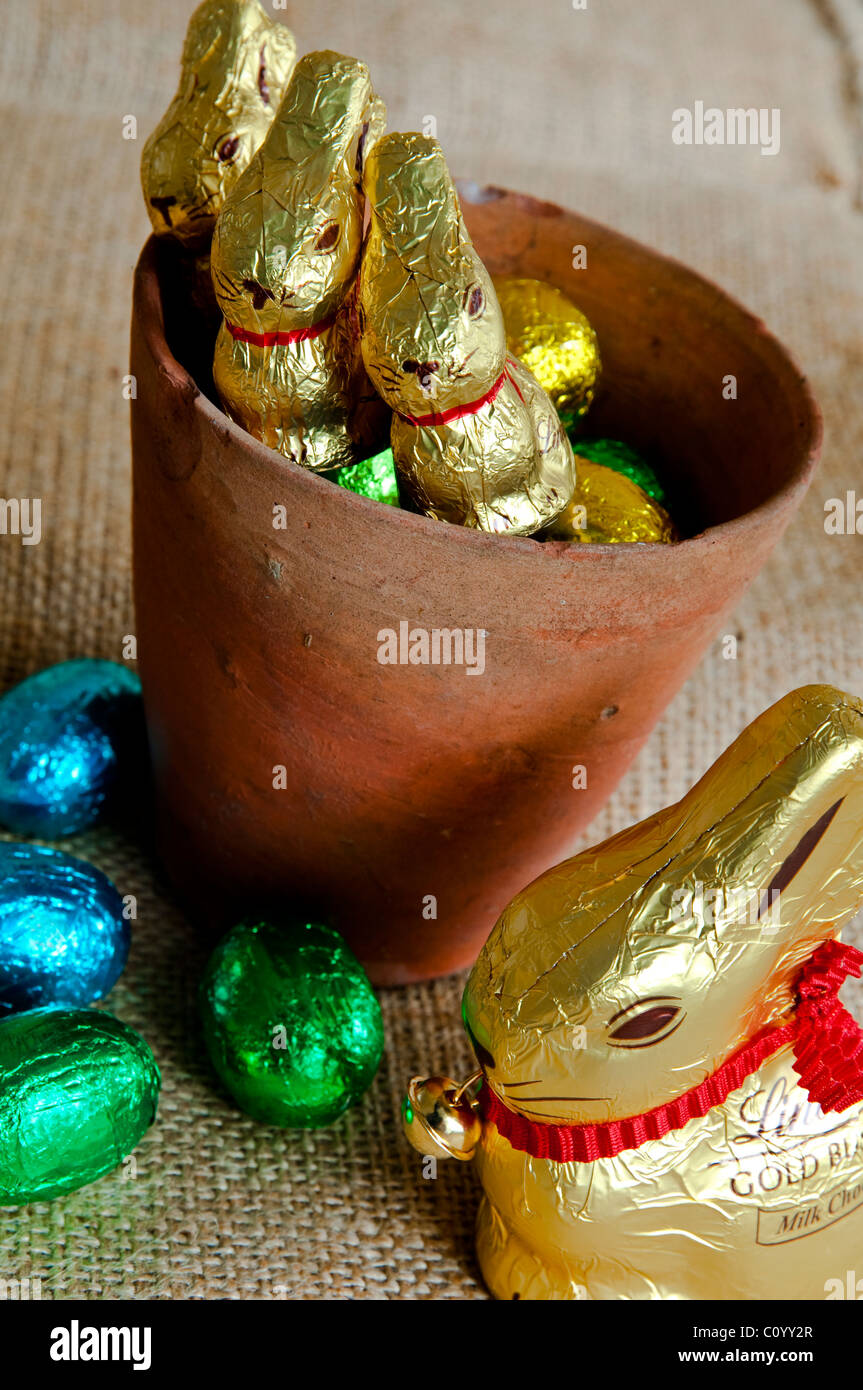 Cute chocolate bunnies - peeping out of an old plant pot - waiting to be found by children on an Easter egg hunt. Stock Photo
