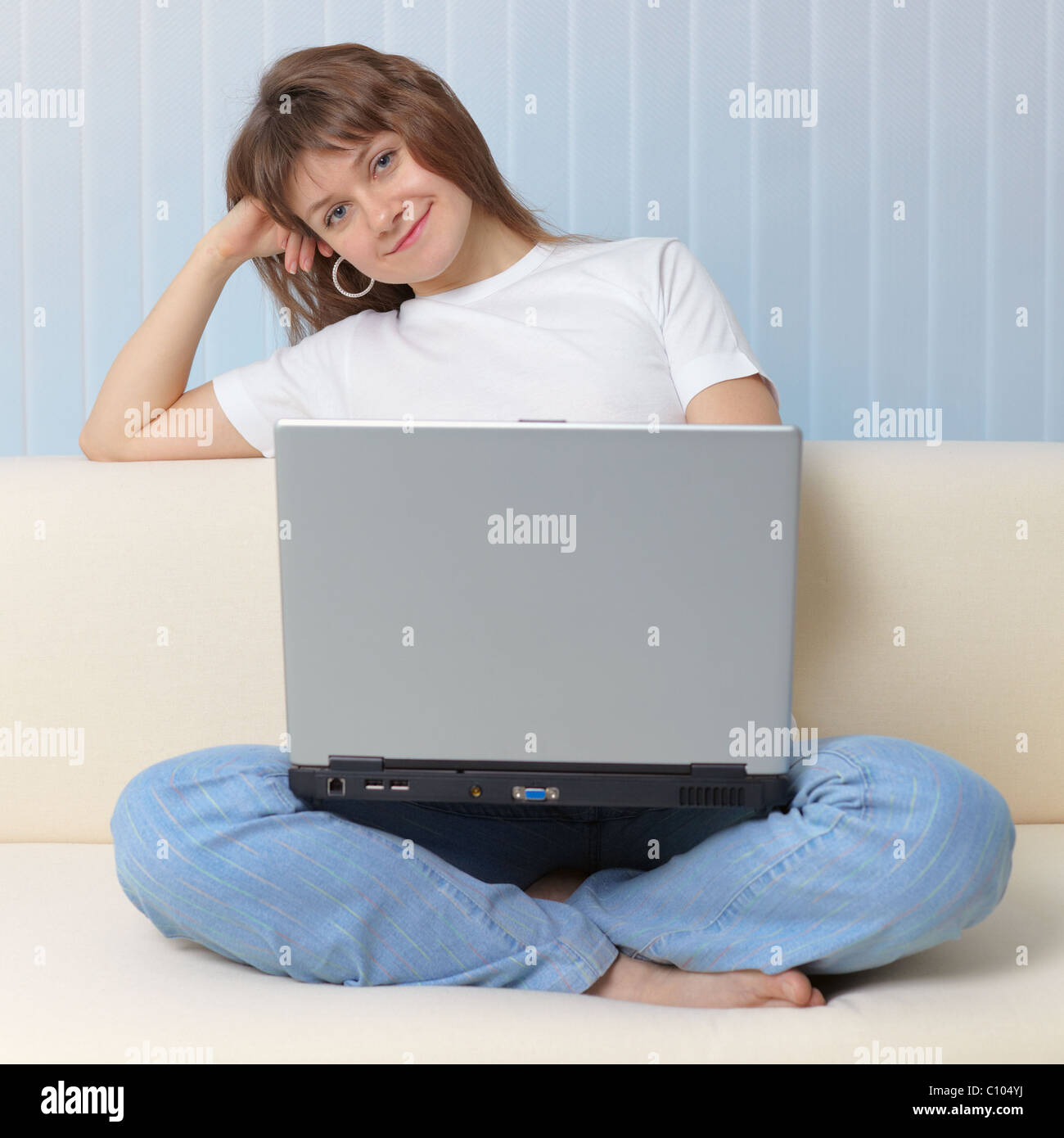 Beautiful young girl with laptop has rest sitting on a sofa Stock Photo