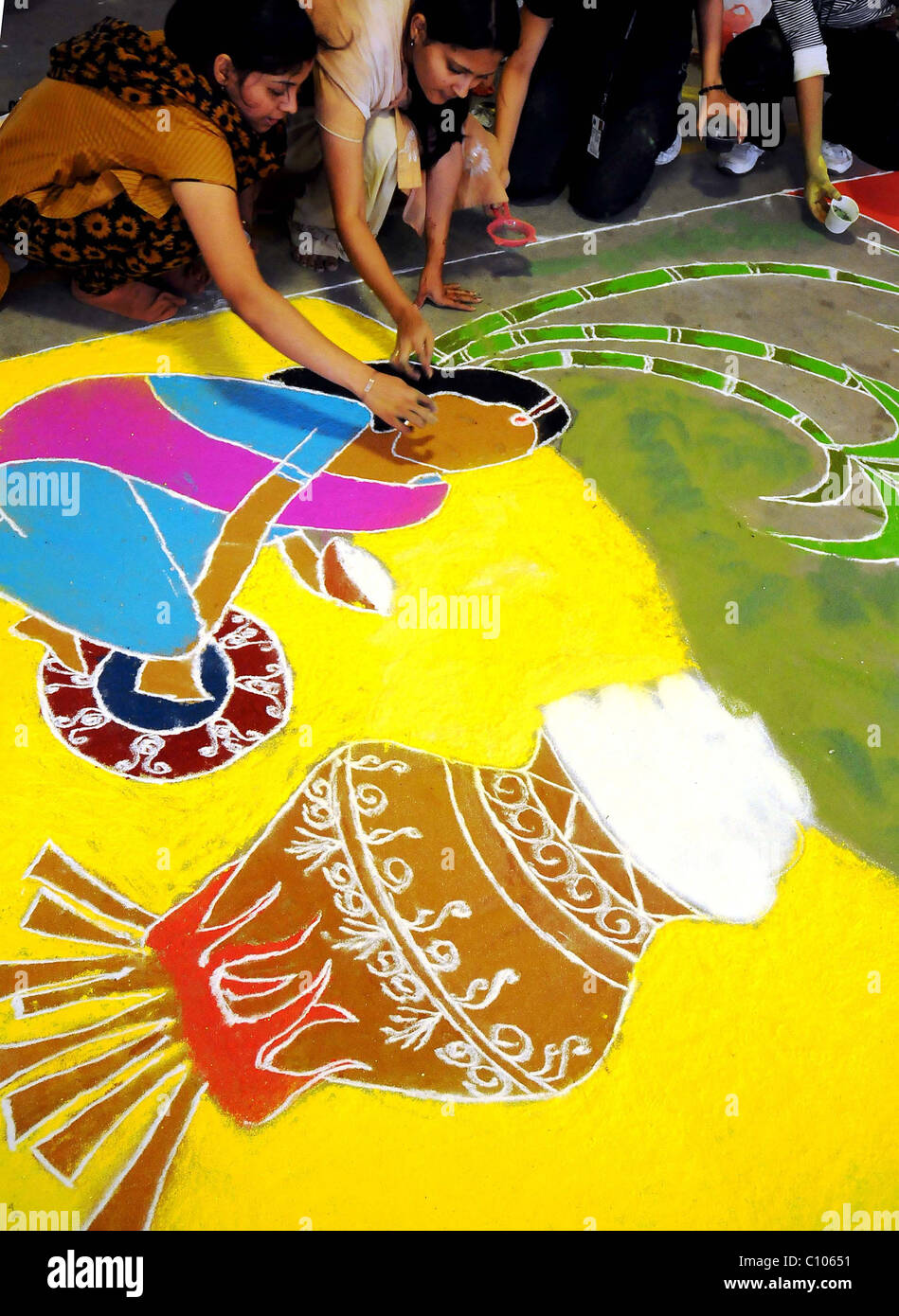 An Indian woman uses colored powder to mark out a Rangoli, a ...
