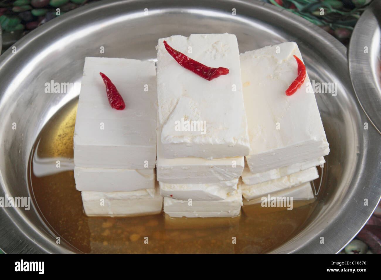 Feta cheese on a silver plate with chilli garnish on display at the street market in Melton Mowbray, Leicestershire, UK. Stock Photo