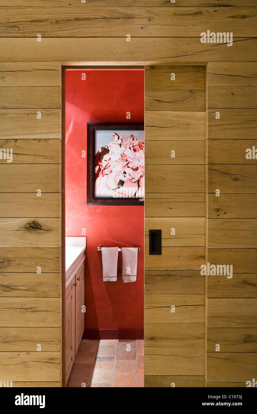 View through open wood panelled sliding door through to bathroom with red walls Stock Photo