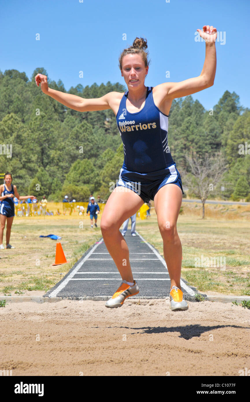 Teenage high school girl athlete soaring in the long jump athletic