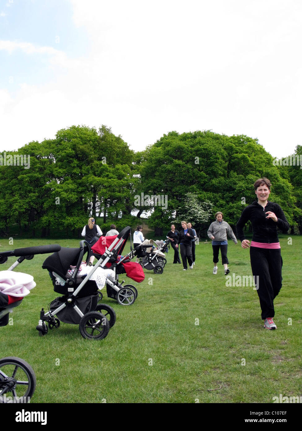 Mothers in a park taking part in an outdoor exercise class Stock Photo