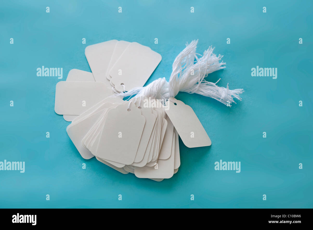white blank price tags with string on blue surface Stock Photo