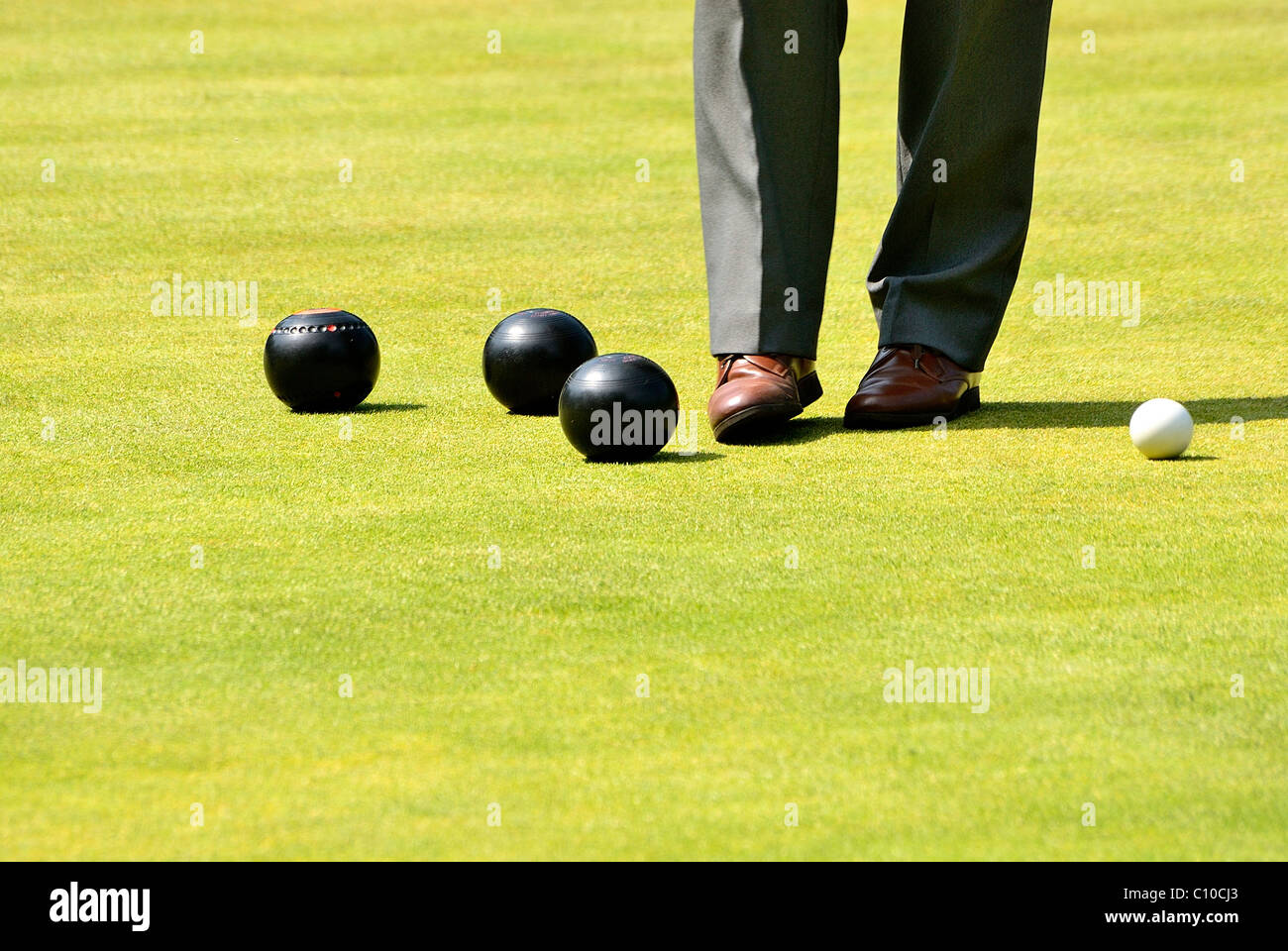 Pair of legs standing over some bowling balls, there is one pair of legs chopped at the knees