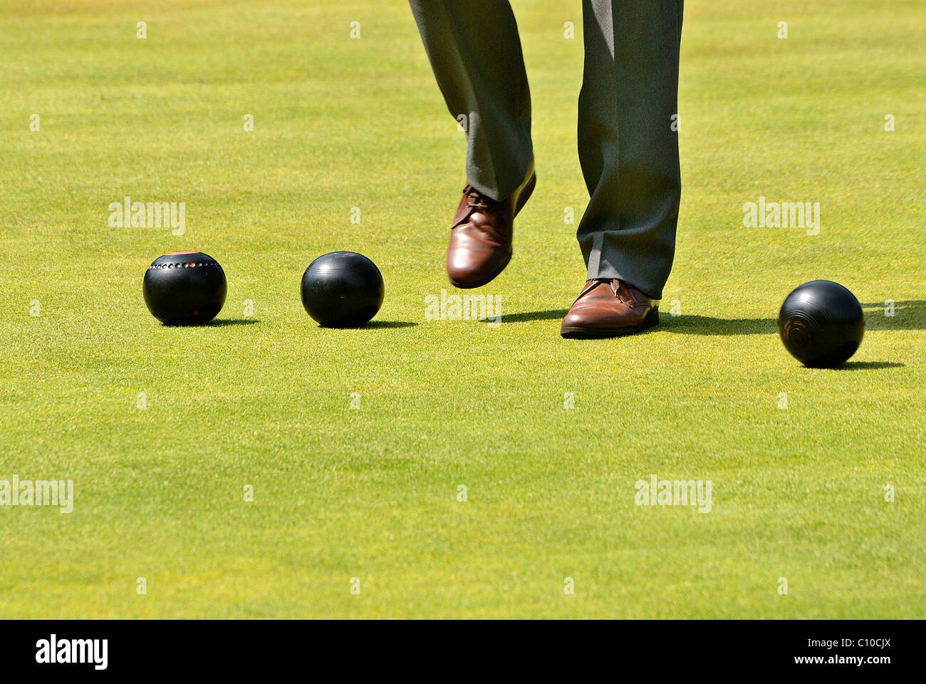 A pair of legs standing over some bowling balls, there is one pair of