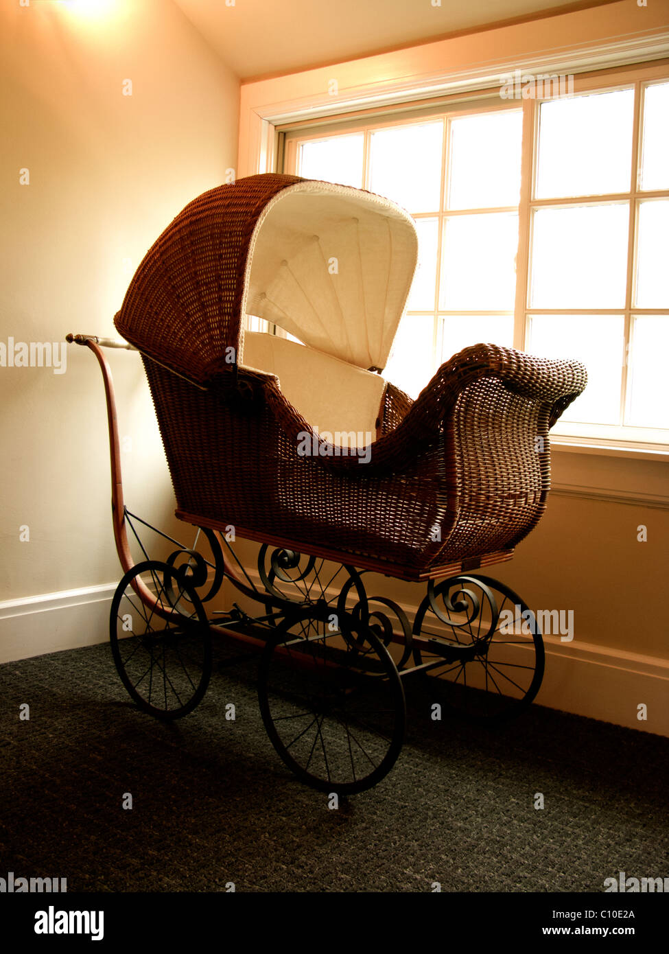 OLD FASHIONED BABY CARRIAGE NEXT TO BRIGHT WINDOW Stock Photo