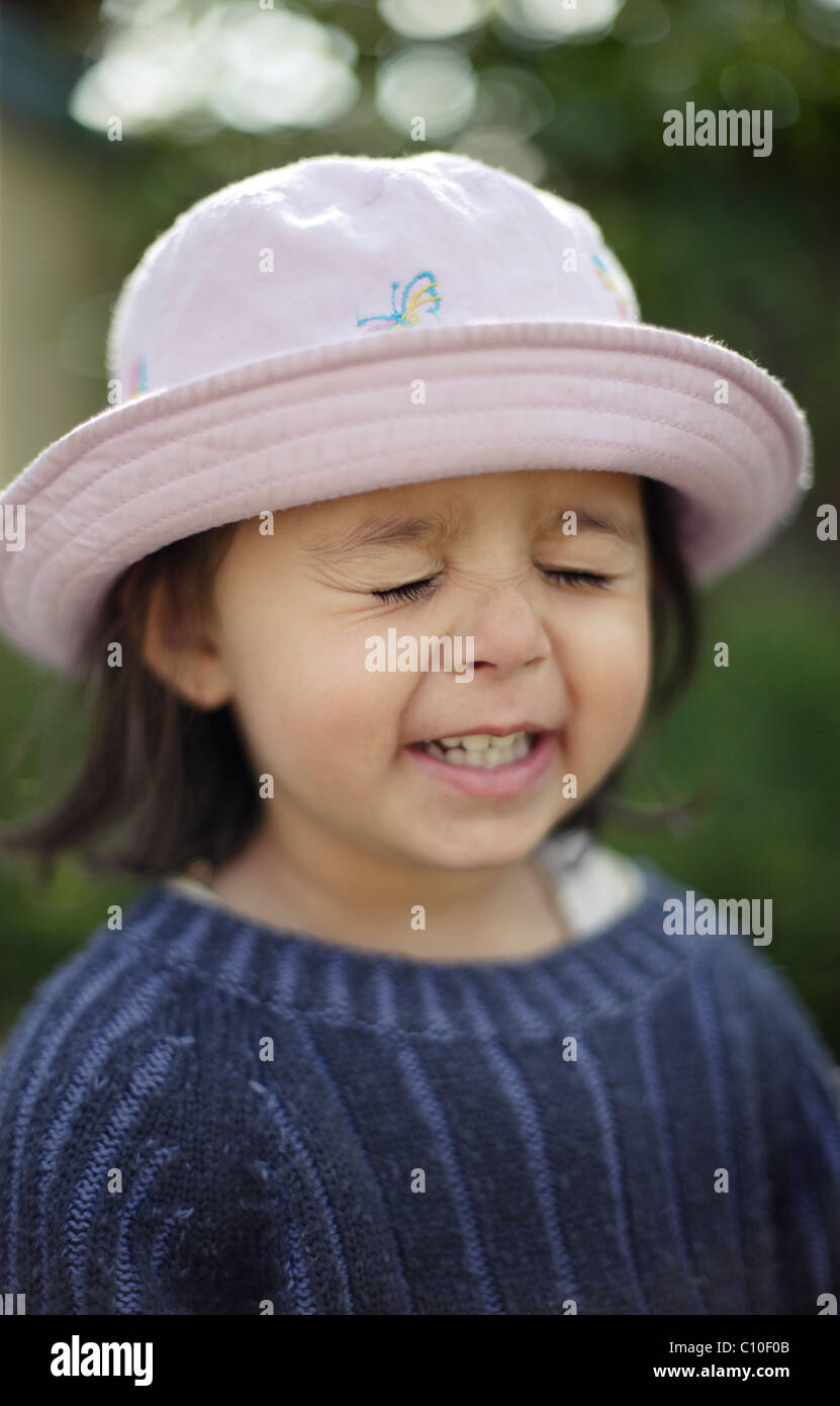Happy two year old girl screws her eyes closed. Stock Photo