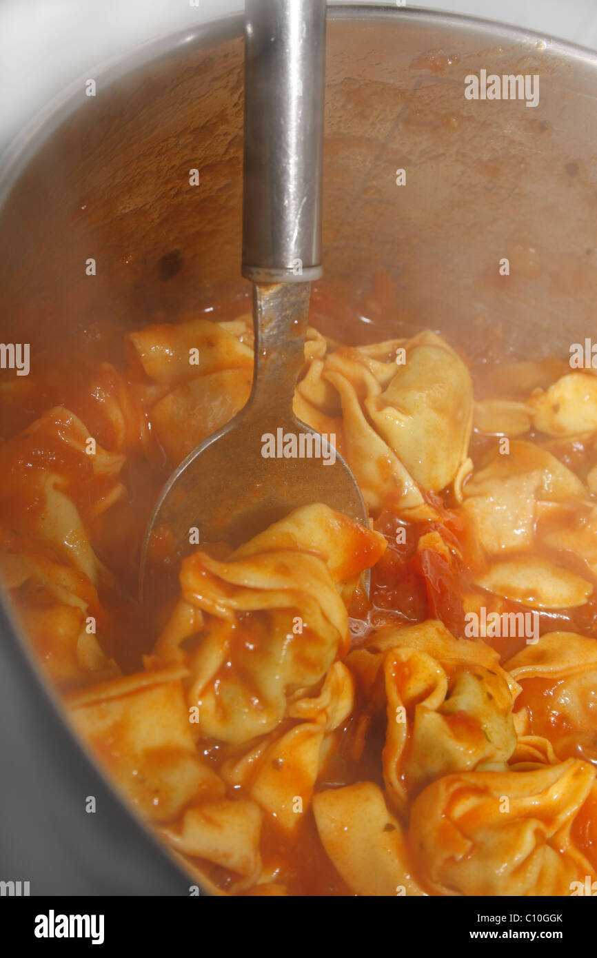 spinach & ricotta tortelloni covered in an italian cherry tomato sauce, cooking in pan Stock