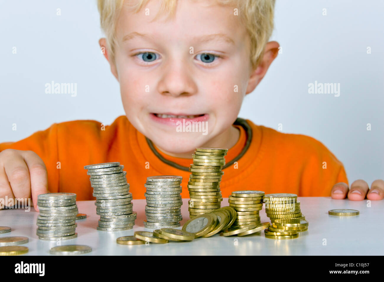 Boy, 5-years old, playing with euro coins, symbolic picture for price drop Stock Photo