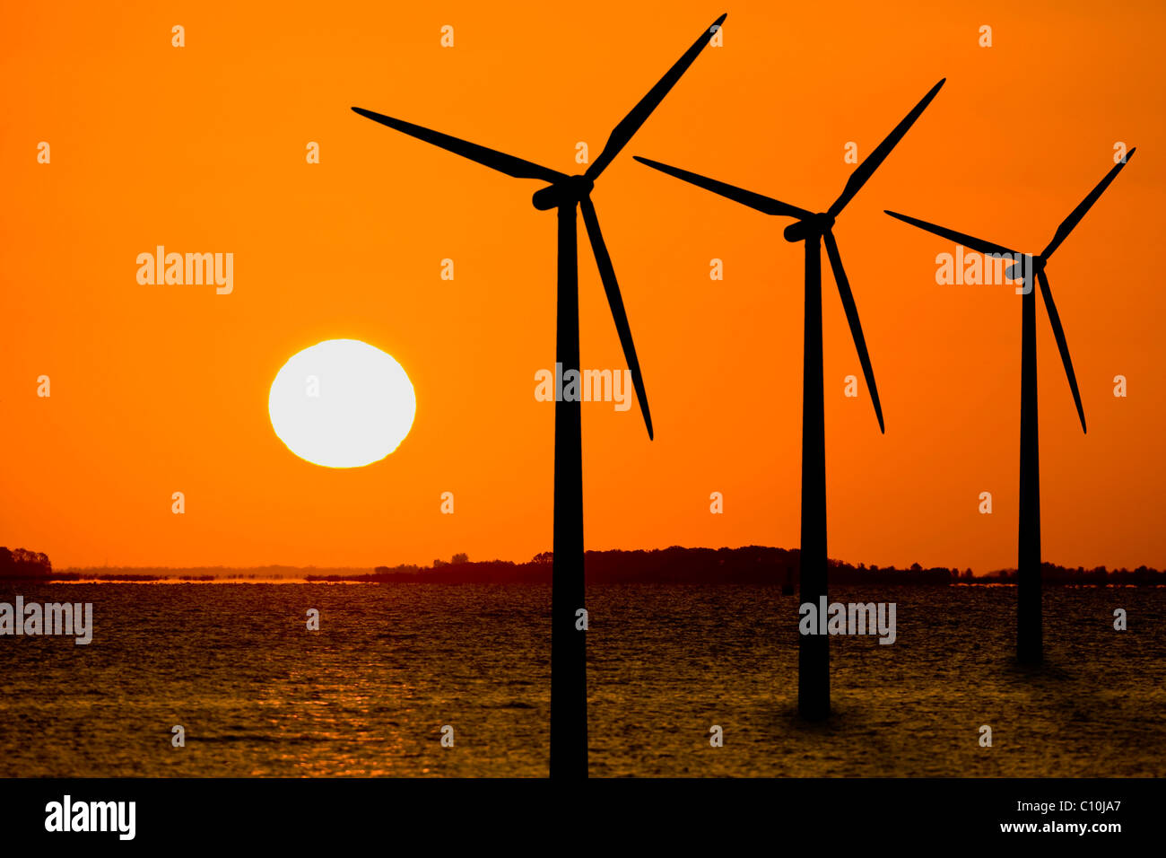 Silhouette of three off-shore wind turbines in sunrise Stock Photo