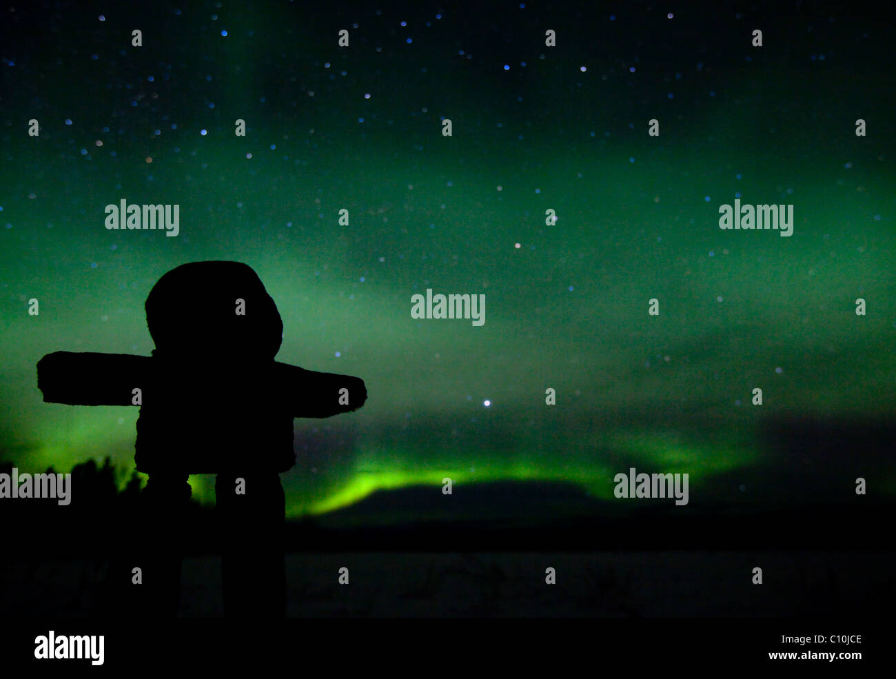 Silhouette of Inuit stone man, inukshuk, inuksuk, stone landmark or cairn, northern polar lights, Aurora Borealis, green Stock Photo