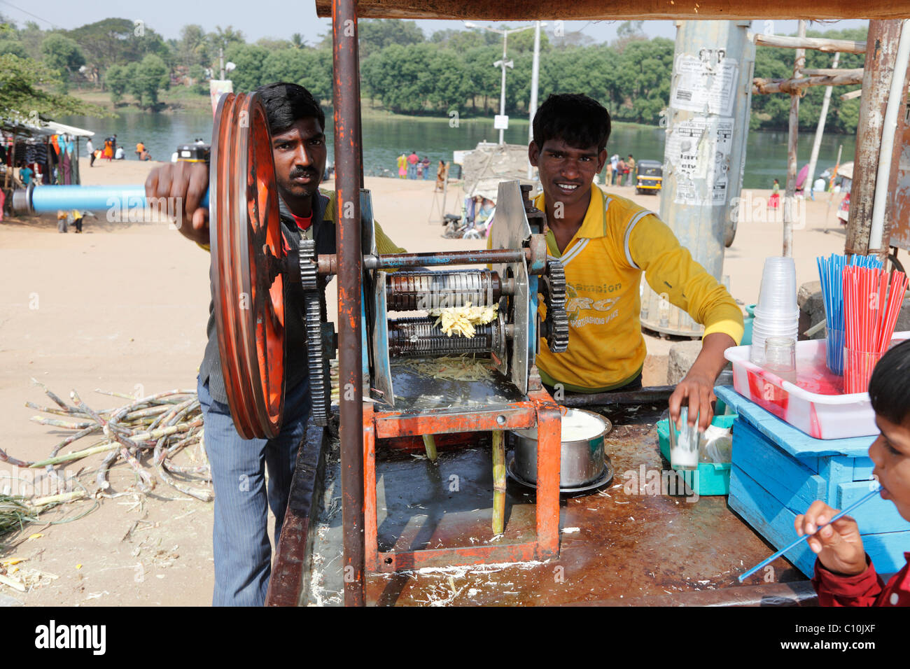 Young men operating sugar cane juice squeezer, Nanjangud, Karnataka