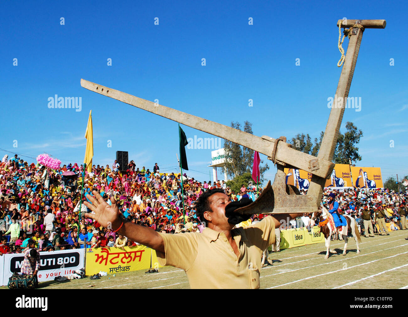 An Indian villager holds up a plough in his mouth as he displays his skills at the Kila Raipur Rural Olympics Ludhiana, India - Stock Photo