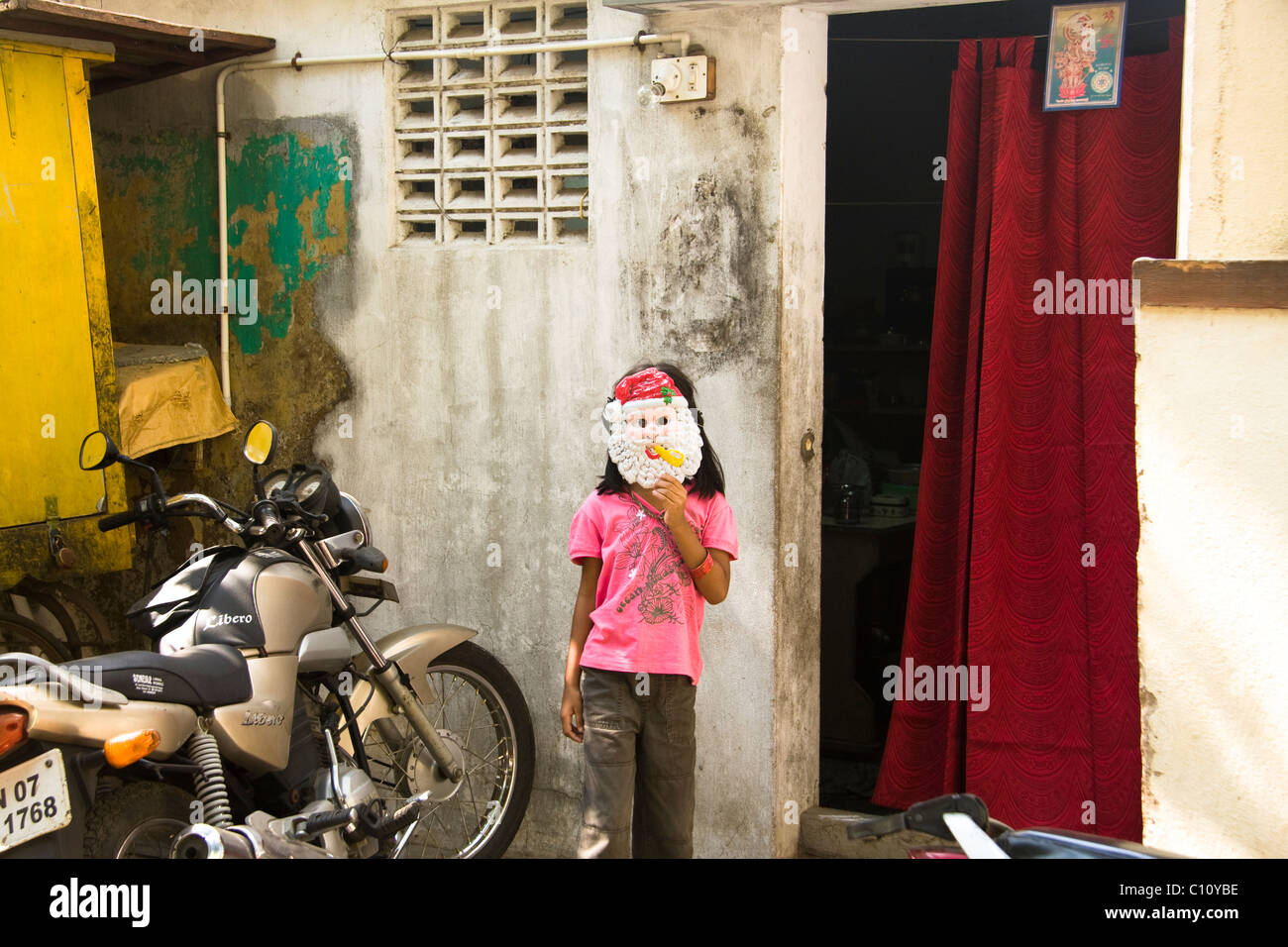 Girl with a Father Christmas mask in from of a house. Stock Photo
